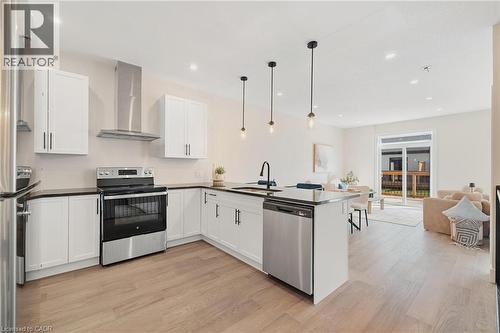 Kitchen featuring appliances with stainless steel finishes, wall chimney exhaust hood, white cabinets, hanging light fixtures, and recessed lighting - 12 Washington Street Unit# 102, Norwich, ON - Indoor Photo Showing Kitchen With Upgraded Kitchen