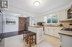 Kitchen with stainless steel appliances, tasteful backsplash, a center island, glass insert cabinets, and a breakfast bar - 