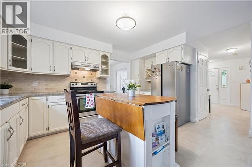 Kitchen featuring glass insert cabinets, decorative backsplash, stainless steel appliances, under cabinet range hood, and white cabinets - 599 Beechwood Drive, Waterloo, ON - Indoor Photo Showing Kitchen