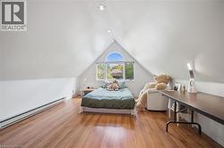 Bedroom with a baseboard radiator, wood finished floors, and lofted ceiling - 
