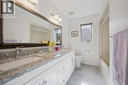 Full bathroom with double vanity, shower / bath combo, and light tile patterned floors - 