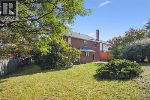 Rear view of house featuring a fenced backyard, a chimney, a patio area, and brick siding - 599 Beechwood Drive, Waterloo, ON - Outdoor