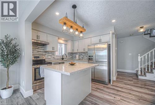 Kitchen with appliances with stainless steel finishes, a textured ceiling, tasteful backsplash, light wood-style floors, and hanging light fixtures - 220 Sienna Crescent, Kitchener, ON - Indoor Photo Showing Kitchen With Stainless Steel Kitchen With Upgraded Kitchen