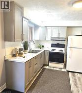 Kitchen featuring gray cabinets, a textured ceiling, white appliances, light countertops, and light wood finished floors - 