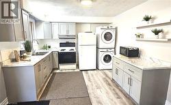 Kitchen featuring gray cabinets, white appliances, light countertops, a textured ceiling, and tasteful backsplash - 