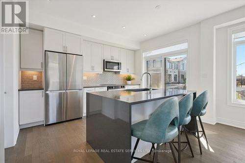 Island & breakfast bar with waterfall countertop - 2180 Postmaster Drive, Oakville, ON - Indoor Photo Showing Kitchen With Stainless Steel Kitchen With Upgraded Kitchen