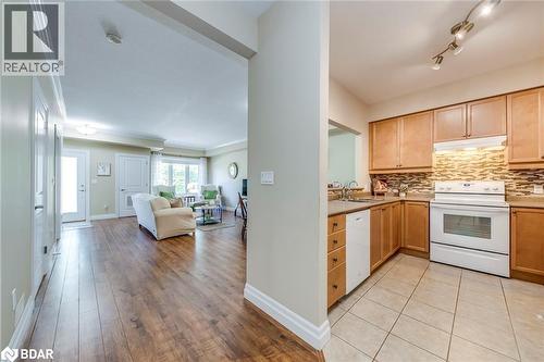 Kitchen with white appliances, decorative backsplash, open floor plan, under cabinet range hood, and light brown cabinetry - 760 Woodhill Drive Unit# 221, Fergus, ON - Indoor Photo Showing Kitchen