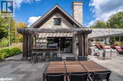View of patio / terrace featuring a pergola, outdoor kitchen, wood burning pizza oven, dining space, and a bar - 
