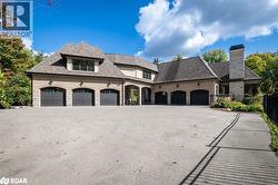 French country style house featuring stone siding, a high end roof, driveway, and an attached garage - 