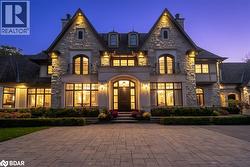 French country inspired facade featuring a balcony, a chimney, stone siding, and french doors - 