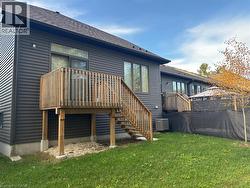 Back of house with roof with shingles, a lawn, a deck, and stairs - 