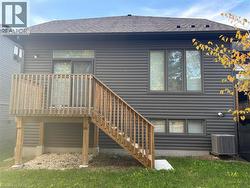 Back of property featuring roof with shingles and a wooden deck - 
