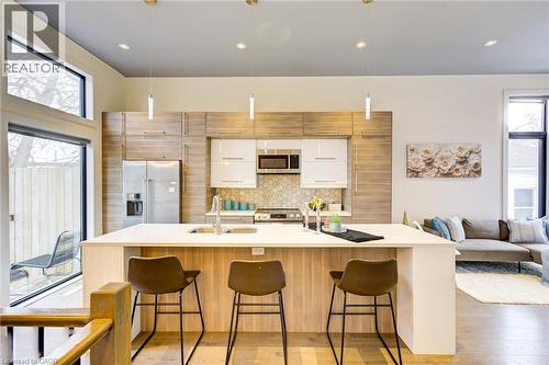 Kitchen with appliances with stainless steel finishes, open floor plan, hanging light fixtures, a large island with sink, and light wood-style floors - 847 Stedwell Street, London, ON - Indoor Photo Showing Kitchen With Upgraded Kitchen
