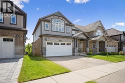 Craftsman-style home featuring driveway, an attached garage, stone siding, and a front yard - 