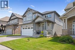 View of front of house with stone siding, asphalt driveway, a front yard, a garage, and board and batten siding - 