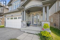 Property entrance with stone siding, board and batten siding, covered porch, an attached garage, and driveway - 