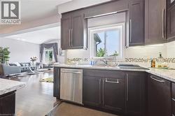 Kitchen with dishwasher, backsplash, dark brown cabinetry, open floor plan, and recessed lighting - 