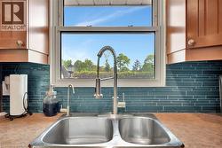 Kitchen view of decorative backsplash, brown cabinets, and dark countertops - 