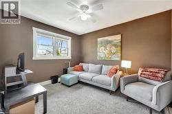 Living area featuring light colored carpet and a ceiling fan - 