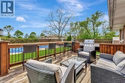 Wooden deck featuring a fenced backyard, grilling area, and an outdoor hangout area - 