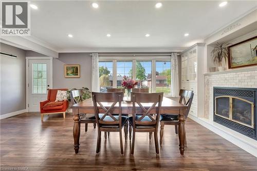 Dining space with ornamental molding, a brick fireplace, dark wood finished floors, healthy amount of natural light, and recessed lighting - 46 Todd Street, Brantford, ON - Indoor Photo Showing Dining Room With Fireplace