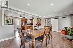 Dining area featuring a barn door, recessed lighting, ornamental molding, wood finished floors, and a ceiling fan - 