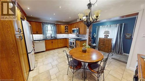 Kitchen with backsplash, appliances with stainless steel finishes, brown cabinetry, a chandelier, and recessed lighting - 113 Edmund Road, Kitchener, ON - Indoor