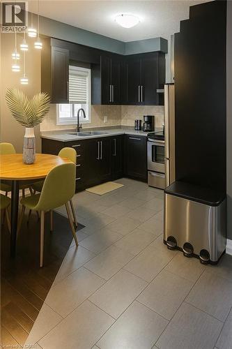 Kitchen with dark cabinetry, backsplash, appliances with stainless steel finishes, pendant lighting, and light tile patterned flooring - 960 Bianca Court Unit# Upper, Kitchener, ON - Indoor