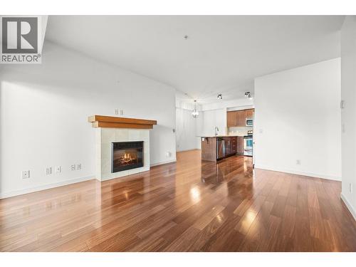 Seamless flow from kitchen, living and dining room with timeless, high end  finishings - 2142 Vasile Road Unit# 202, Kelowna, BC - Indoor Photo Showing Living Room With Fireplace