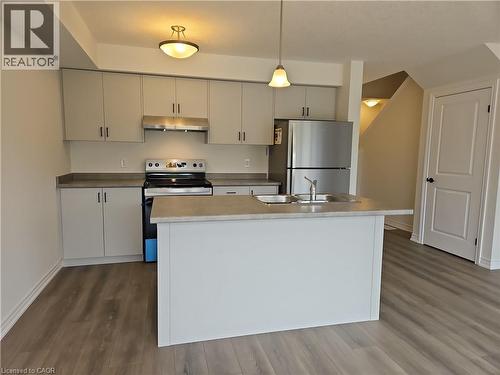 Kitchen with stainless steel appliances, decorative light fixtures, dark wood-style flooring, and under cabinet range hood - 261 Benninger Drive Unit# Upper, Kitchener, ON - Indoor Photo Showing Kitchen With Stainless Steel Kitchen With Double Sink