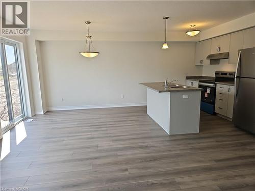 Kitchen featuring stainless steel appliances, dark countertops, dark wood-type flooring, an island with sink, and white cabinets - 261 Benninger Drive Unit# Upper, Kitchener, ON - Indoor Photo Showing Kitchen With Stainless Steel Kitchen
