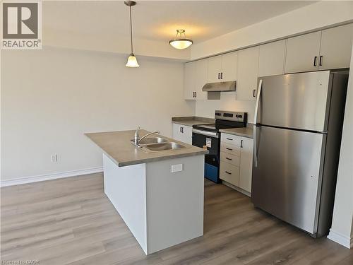 Kitchen with stainless steel appliances, dark wood-style floors, pendant lighting, under cabinet range hood, and white cabinetry - 261 Benninger Drive Unit# Upper, Kitchener, ON - Indoor Photo Showing Kitchen With Stainless Steel Kitchen With Double Sink