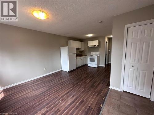 Kitchen featuring white appliances, white cabinetry, a textured ceiling, open floor plan, and dark wood finished floors - 17 St Leger Street, Kitchener, ON - Indoor Photo Showing Kitchen