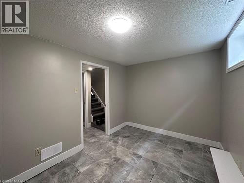 Unfurnished room with a textured ceiling and stairway - 17 St Leger Street, Kitchener, ON - Indoor Photo Showing Other Room
