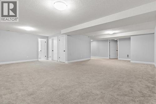 Finished basement with a textured ceiling and light carpet - 556 Mayapple Street, Waterloo, ON - Indoor