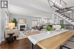 Dining room with a glass covered fireplace, wood finished floors, a chandelier, recessed lighting, and stairway - 