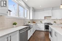 Kitchen with white cabinetry, light stone countertops, and recessed lighting - 
