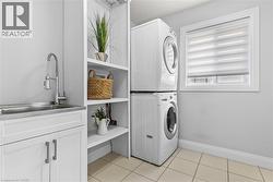 Washroom featuring stacked washer / drying machine and light tile patterned floors - 