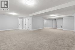 Finished basement with a textured ceiling and light carpet - 