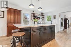 Kitchen with decorative light fixtures, light stone counters, a breakfast bar, and light wood-type flooring - 