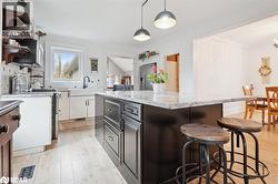 Kitchen featuring a breakfast bar area, light stone counters, white cabinets, light wood-style floors, and a kitchen island - 