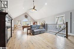 Living area featuring high vaulted ceiling, light wood finished floors, healthy amount of natural light, a tiled fireplace, and recessed lighting - 
