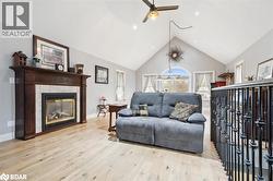 Living area featuring high vaulted ceiling, light wood-style flooring, a tile fireplace, ceiling fan, and recessed lighting - 