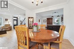 Dining space featuring light wood-style floors, crown molding, a chandelier, and stairway - 
