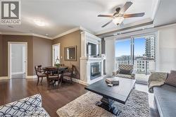 Living area featuring ornamental molding, dark wood-style floors, a glass covered fireplace, and a ceiling fan - 