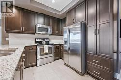 Kitchen with dark brown cabinetry, appliances with stainless steel finishes, and light tile patterned floors - 