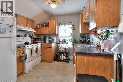 Kitchen with white appliances, dark countertops, under cabinet range hood, and brown cabinets - 50 Walnut Street, Kitchener, ON - Indoor Photo Showing Kitchen