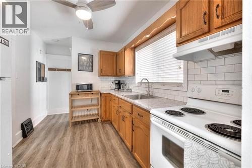 Kitchen with white appliances, tasteful backsplash, under cabinet range hood, light wood-type flooring, and light countertops - 50 Walnut Street, Kitchener, ON - Indoor Photo Showing Kitchen