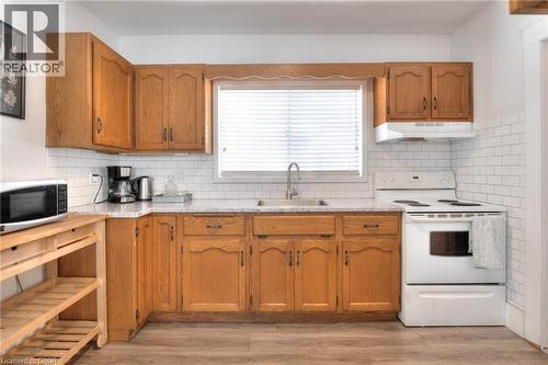 Kitchen with white electric range, light countertops, brown cabinets, and light wood-type flooring - 50 Walnut Street, Kitchener, ON - Indoor Photo Showing Kitchen