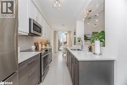 Kitchen with stainless steel appliances, white cabinetry, decorative backsplash, light tile patterned floors, and light stone countertops - 